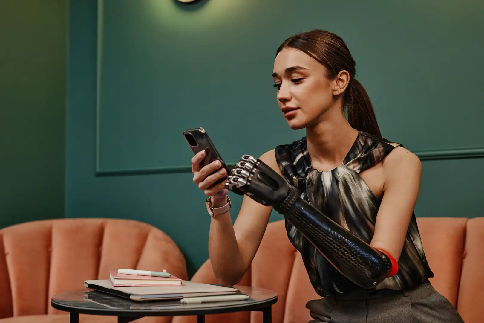 A woman with one arm sits in a cafe using her phone.